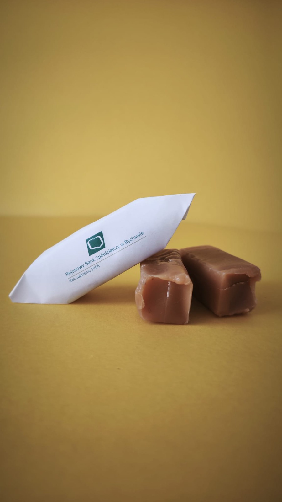 Krówki reklamowe i papierek z zielonym logo Rejonowego Banku Spółdzielczego w Bychawie